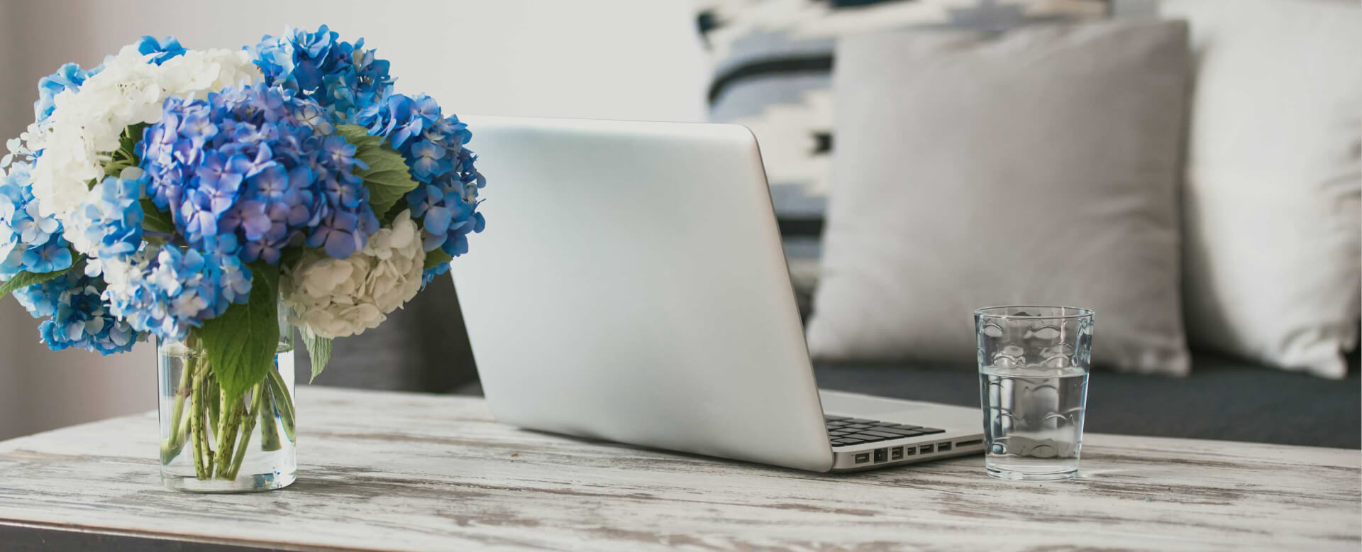 Blue and White flowers on a table with a silver laptop
